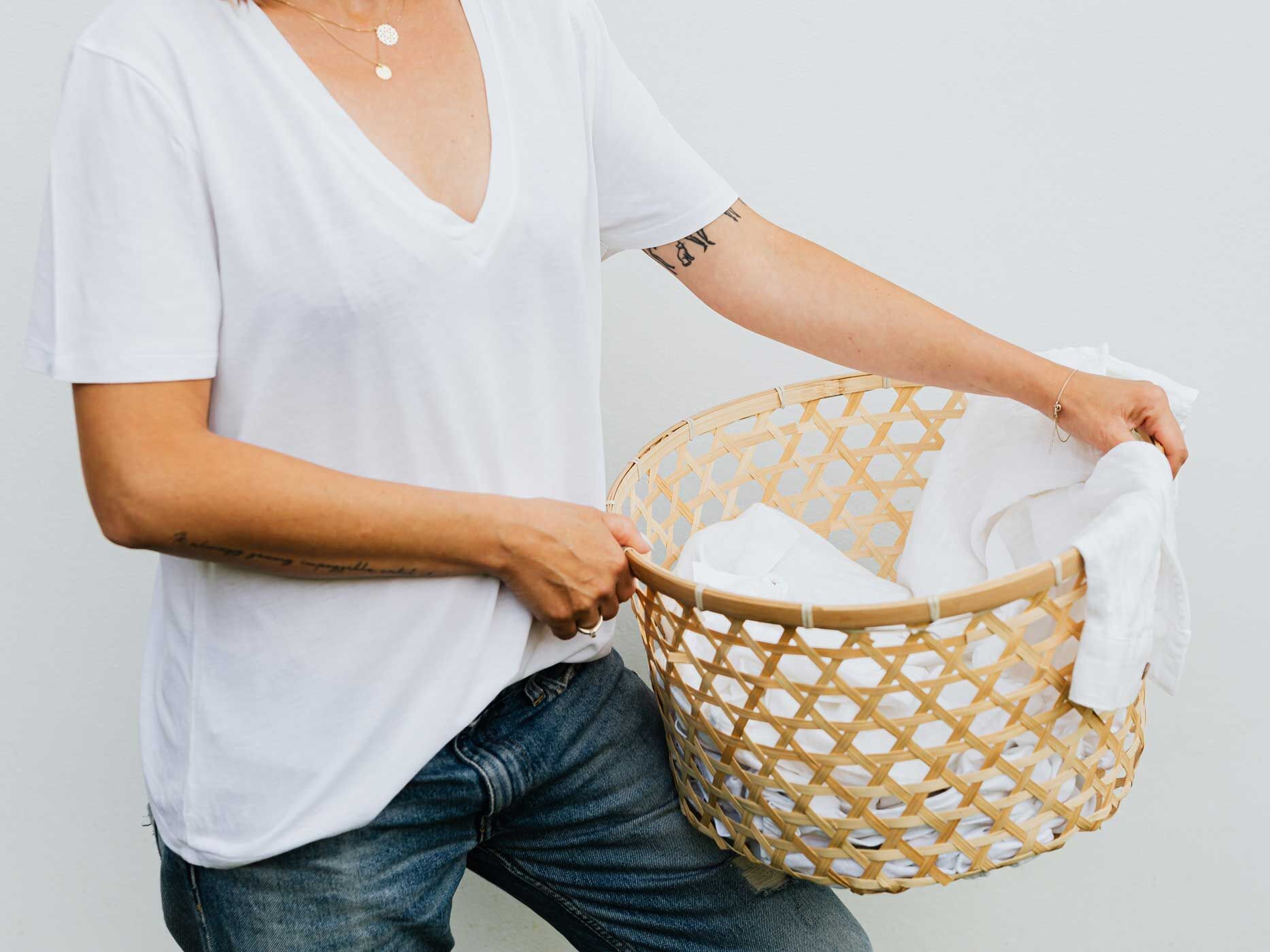 Frau im weißen Shirt mit einem Wäschekorb in der Hand