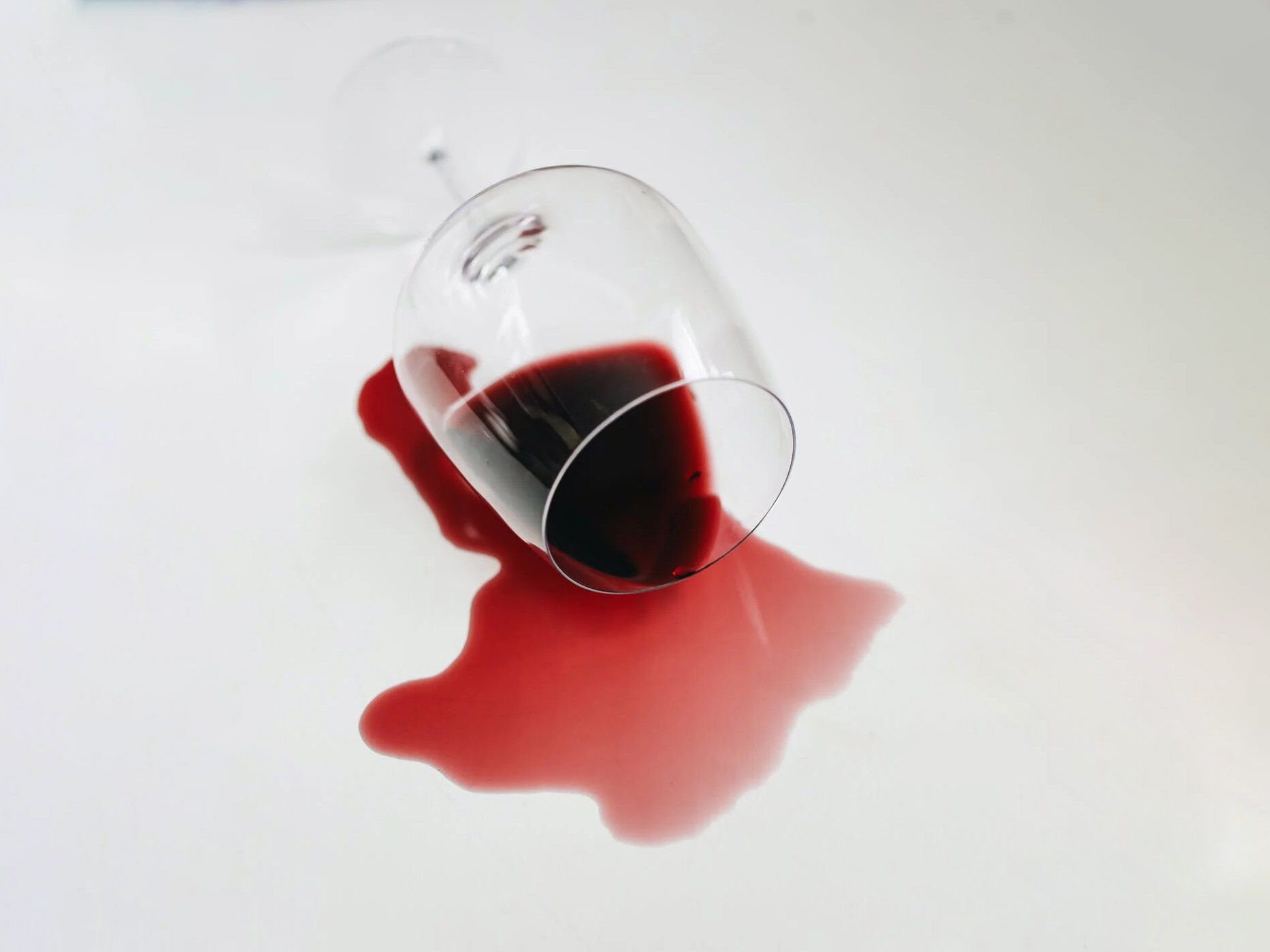 Rotwein fließt aus einem Weinglas auf den Tisch