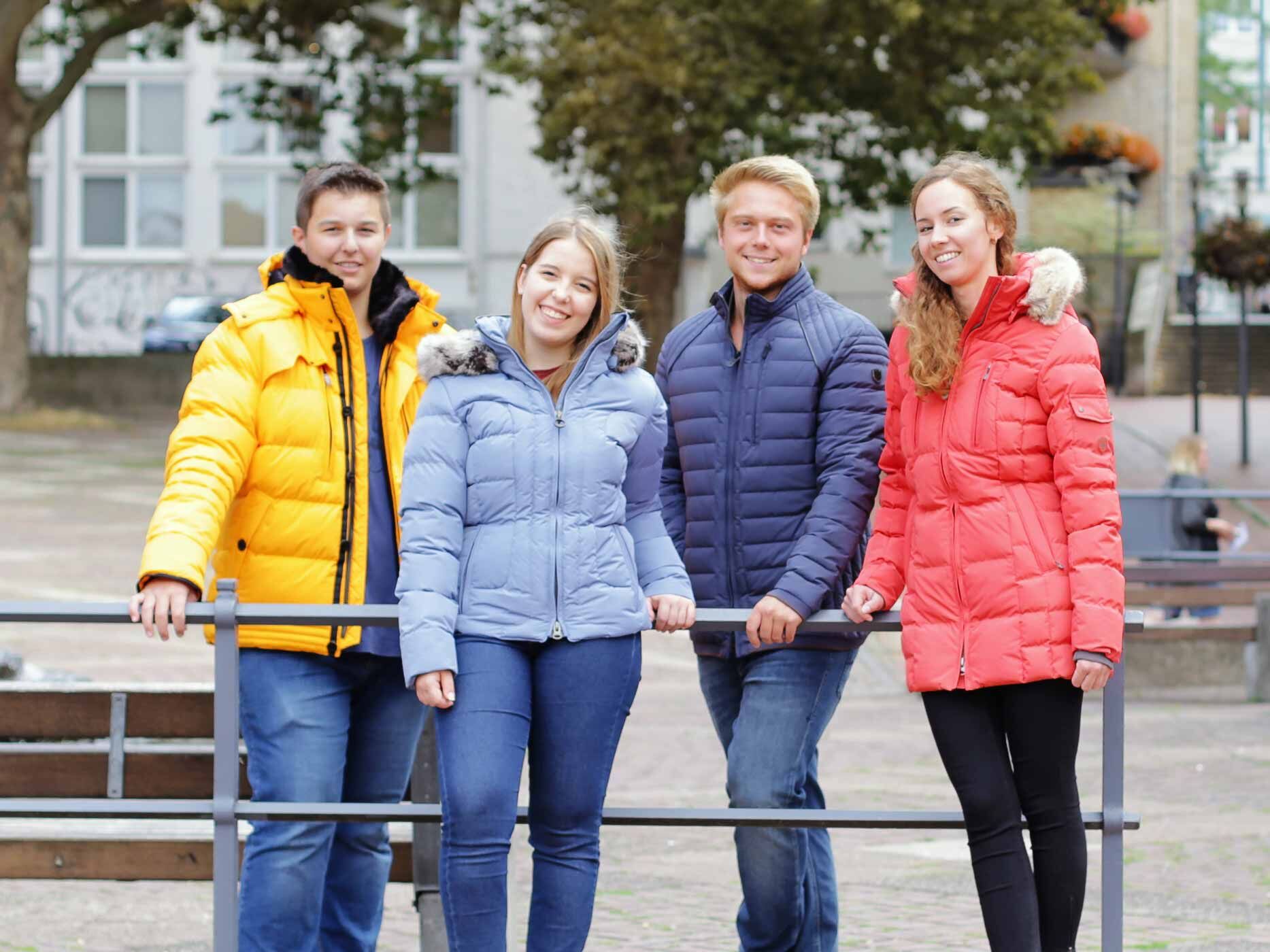 Zwei Jungen und zwei Mädchen stehen in einer Gruppe zusammen in der Natur, sie tragen alle Wellensteyn Jacken in verschiedenen Farben.