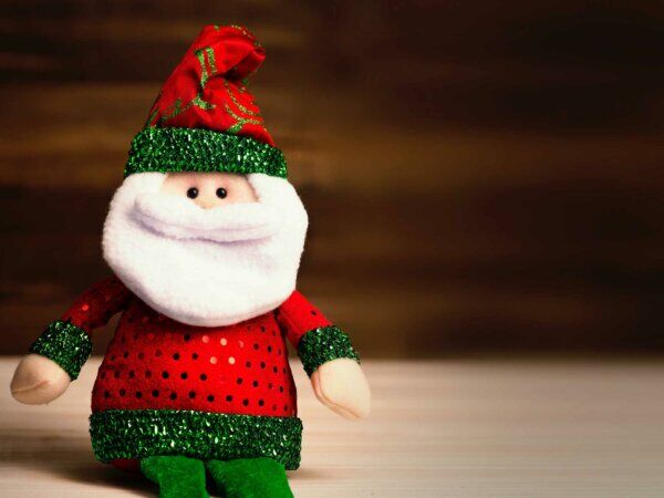 Ein Weihnachtsmann Kuscheltier sitzt auf einem Tisch. 