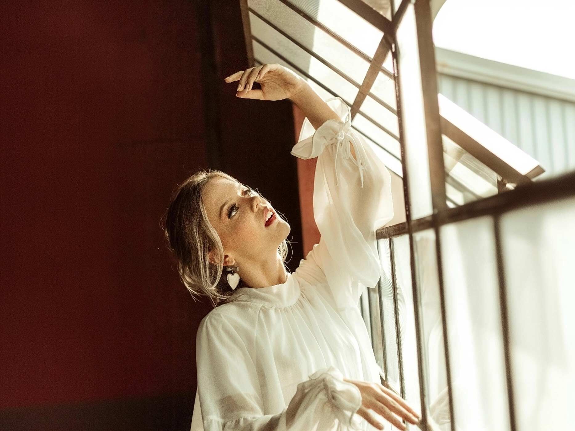 Eine Frau trägt eine weiße, sehr verspielte Bluse mit Rüschen und Schleifchen.