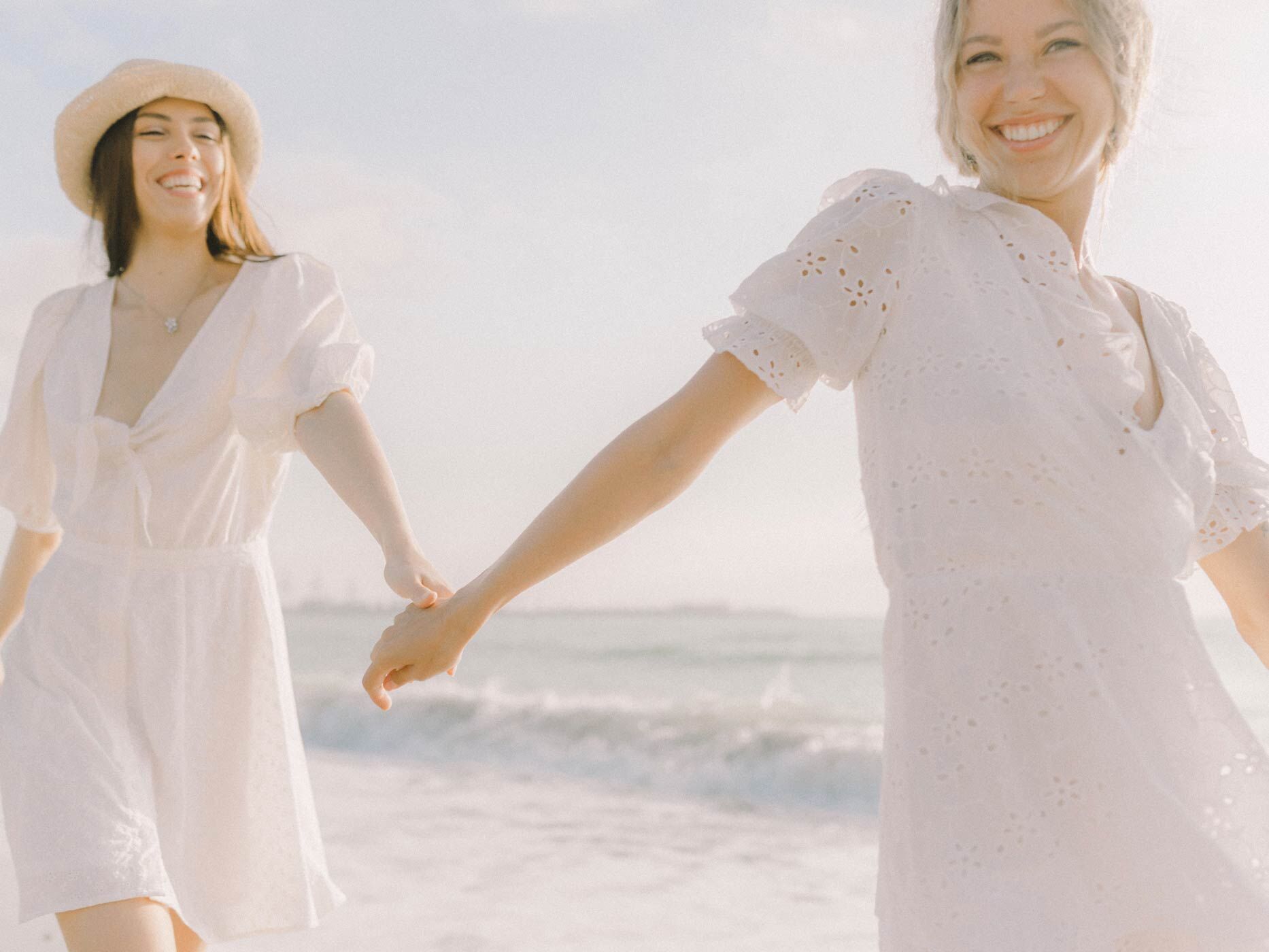 Zwei Frauen tragen am Strand jeweils ein kurzes, weißes Blusenkleid