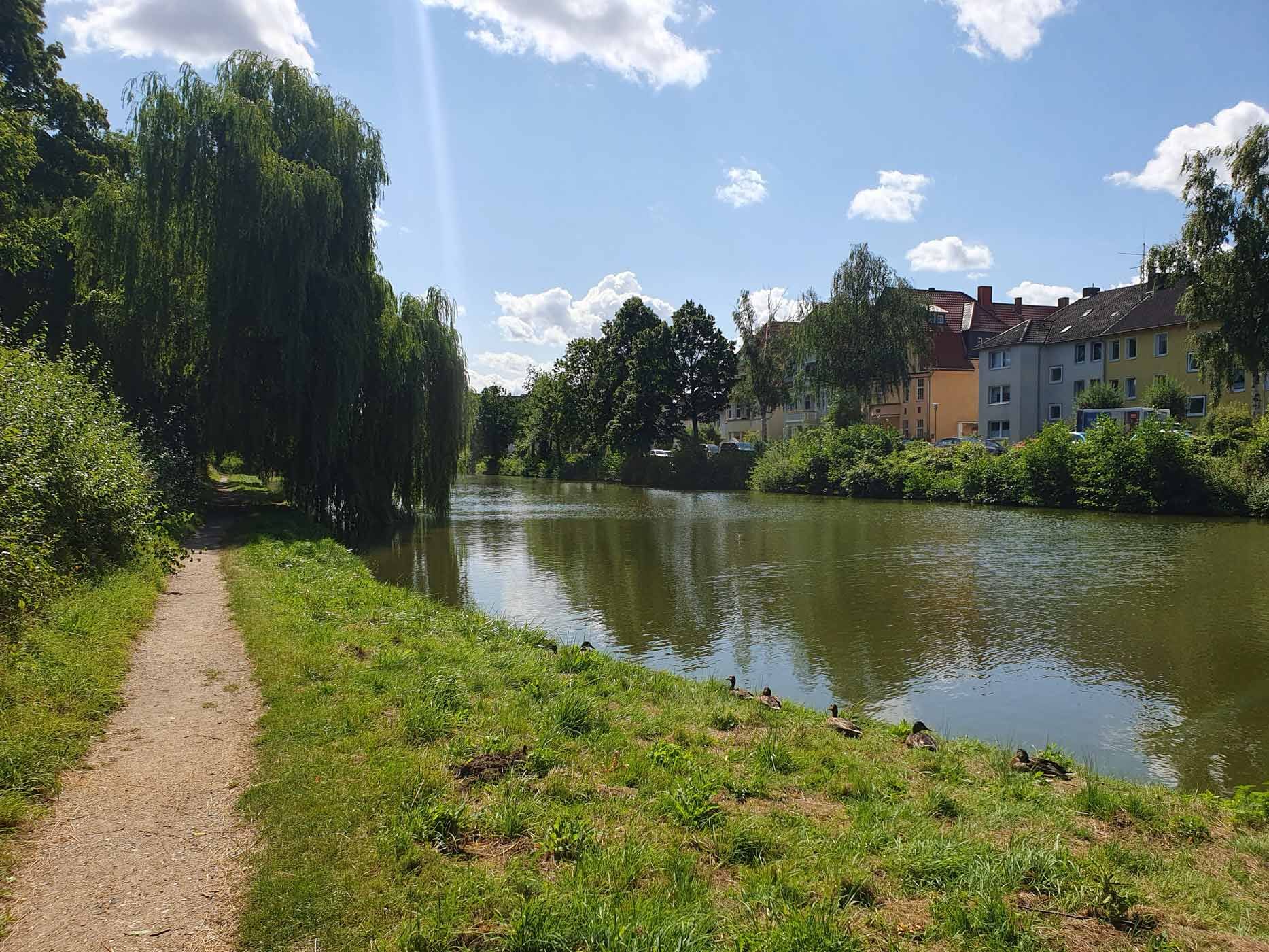 Zu sehen ist ein Gewässer, dass in einem Graben entlang an alten Fachwerkhäusern verläuft.