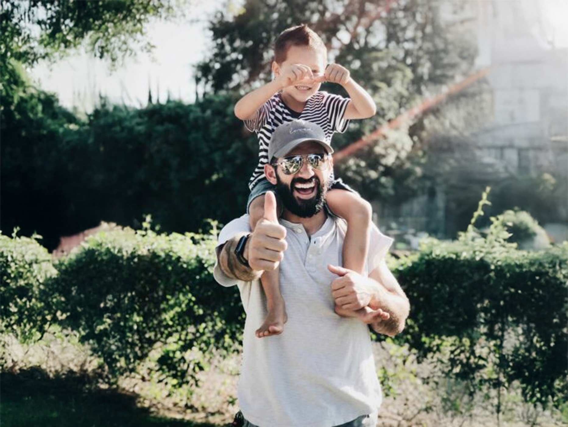 Ein Vater trägt sein Kind glücklich auf den Schultern.