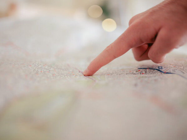 Eine Person zeigt mit dem Finger auf einen Punkt auf einer Stadtkarte.