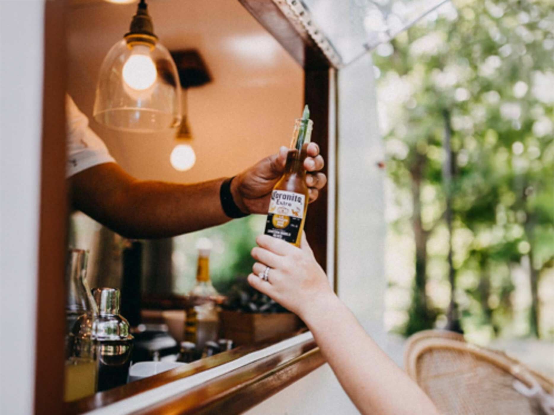 Jemand kauft ein Bier an einer Bar. 