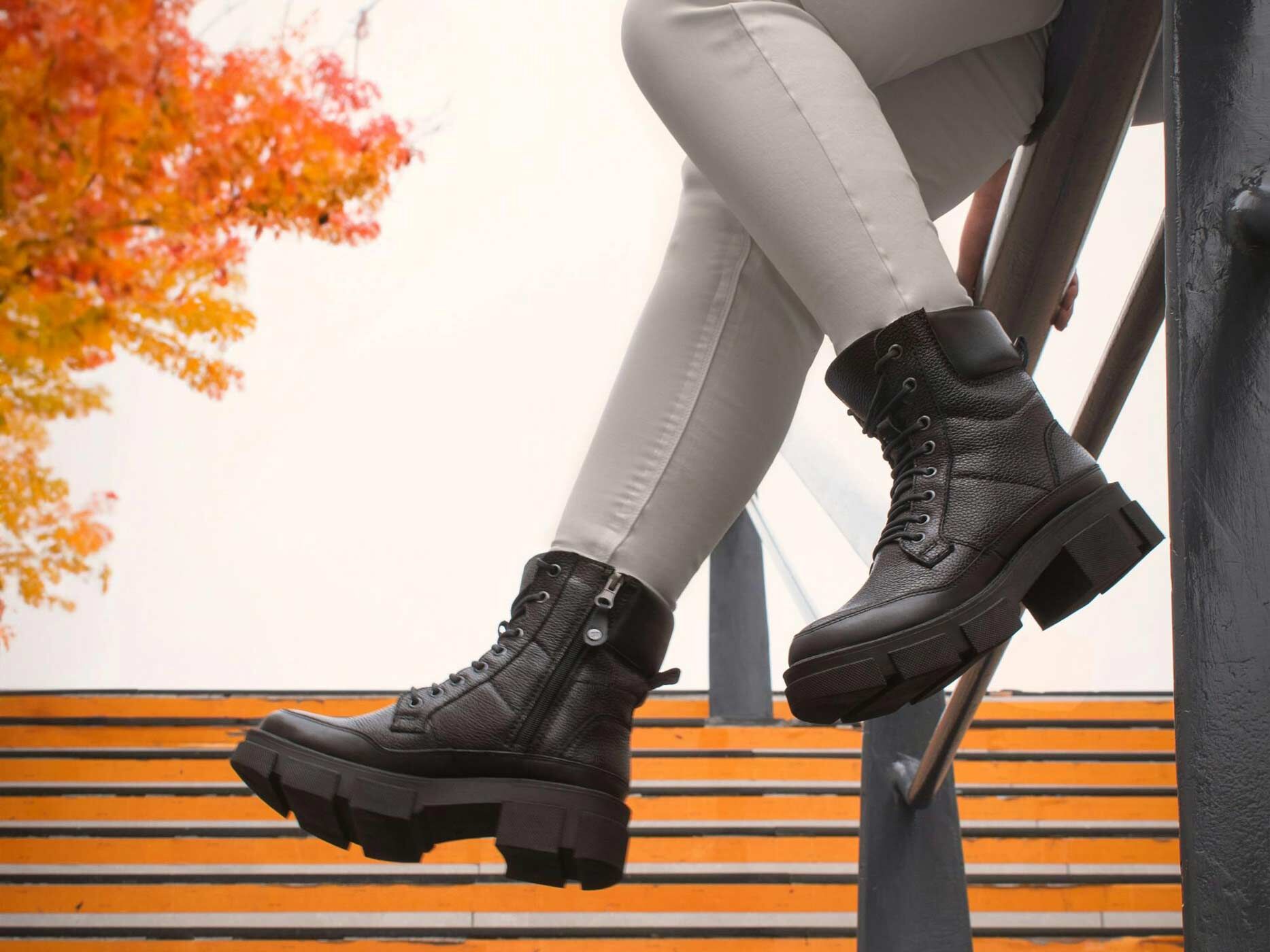 Nahaufnahme von zwei schwarzen Boots, die zu einer grauen Skinny Jeans getragen werden.