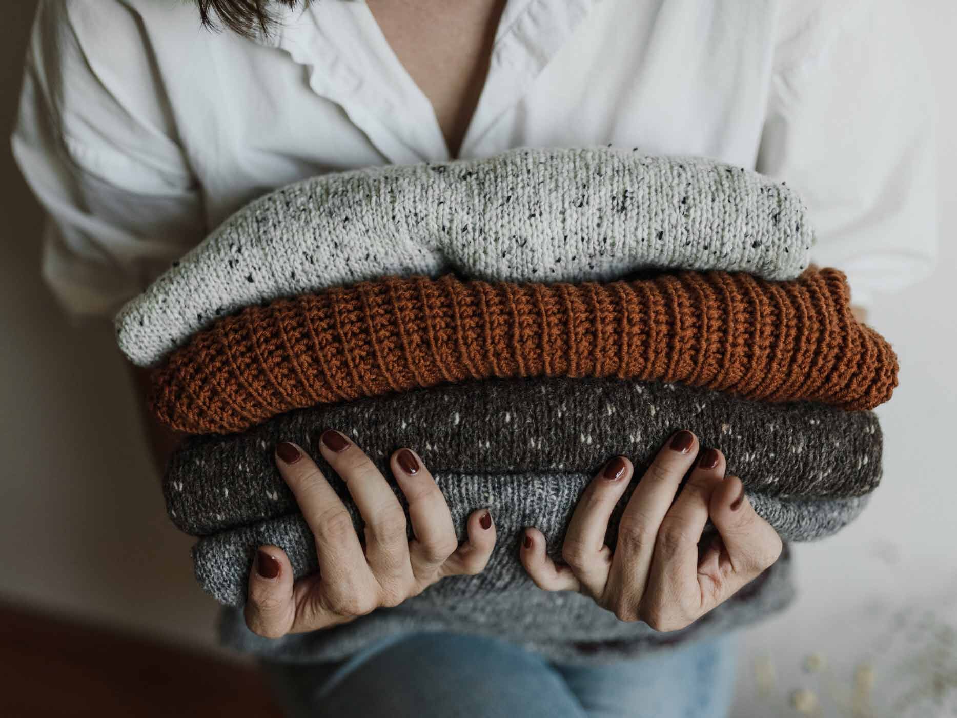 Frau hält einen Stapel Kleidung in den Händen