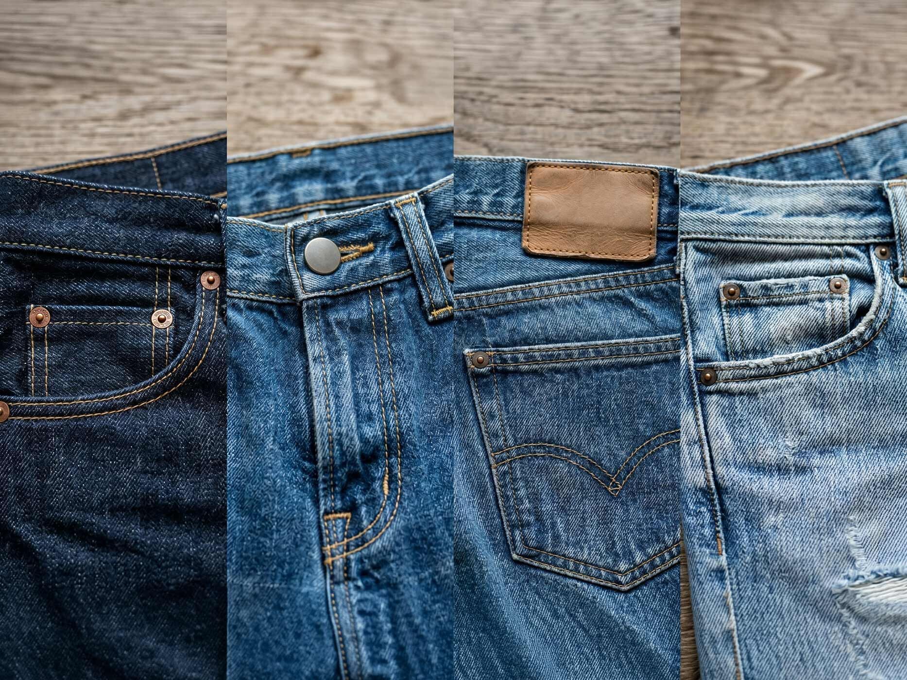 Detailaufnahme mehrerer Jeanshosen in verschiedenen Waschungen. Sichtbar sind typische Merkmale wie Taschen, Nieten, Kontrastnähte und ein Lederpatch am Bund.