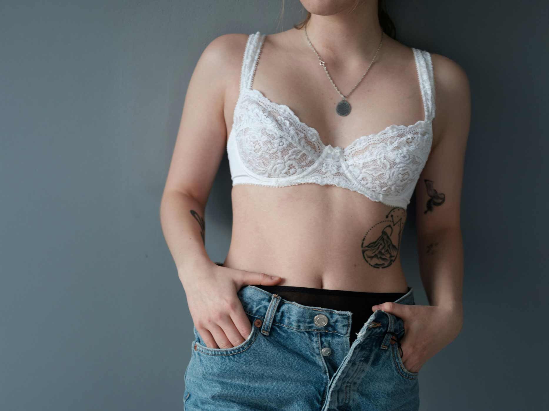 Eine Frau trägt eine hellblaue Jeans und einen weißen Spitzen-BH.