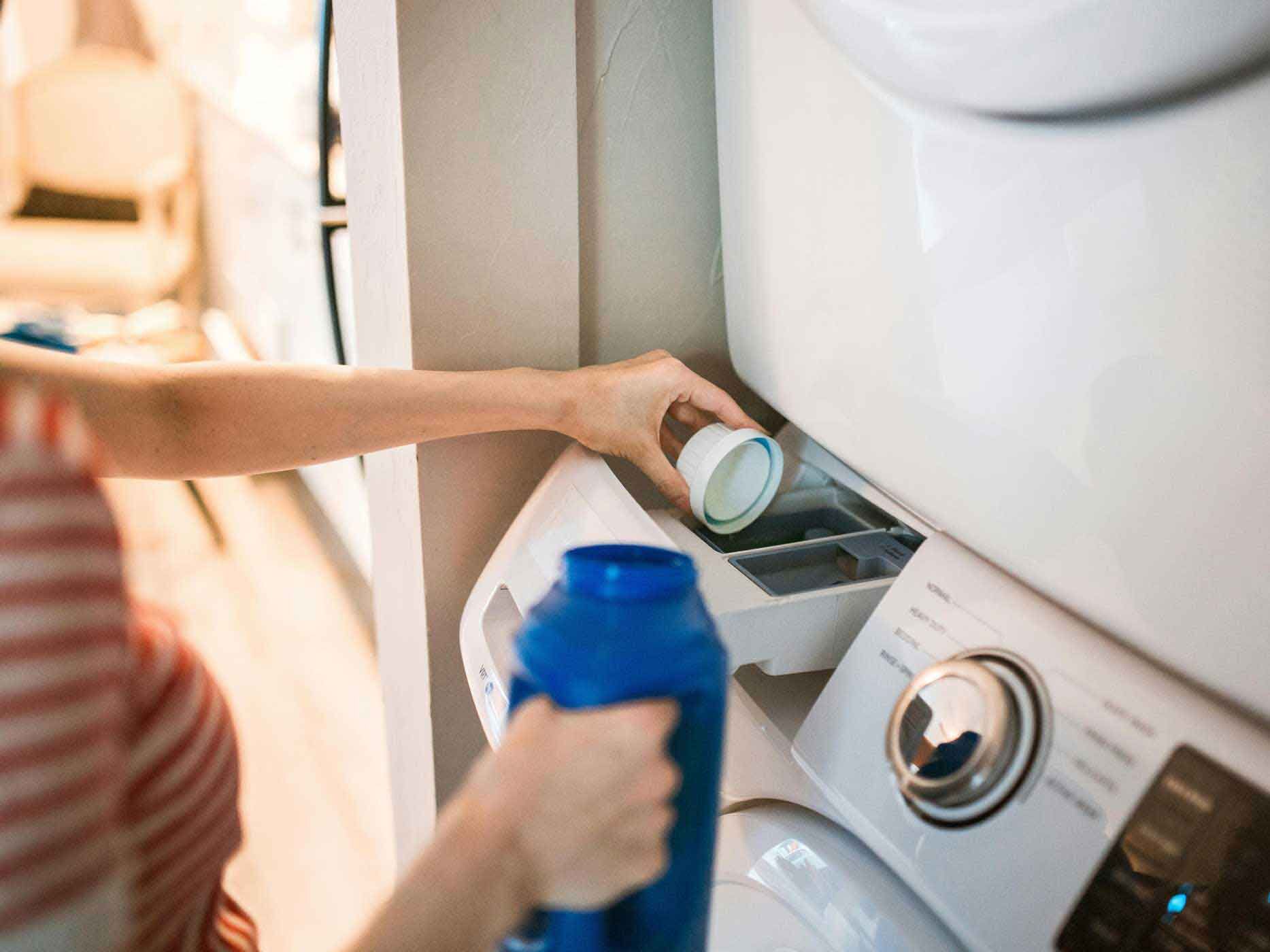 Eine Frau kippt Waschmittel in die Waschmaschine.