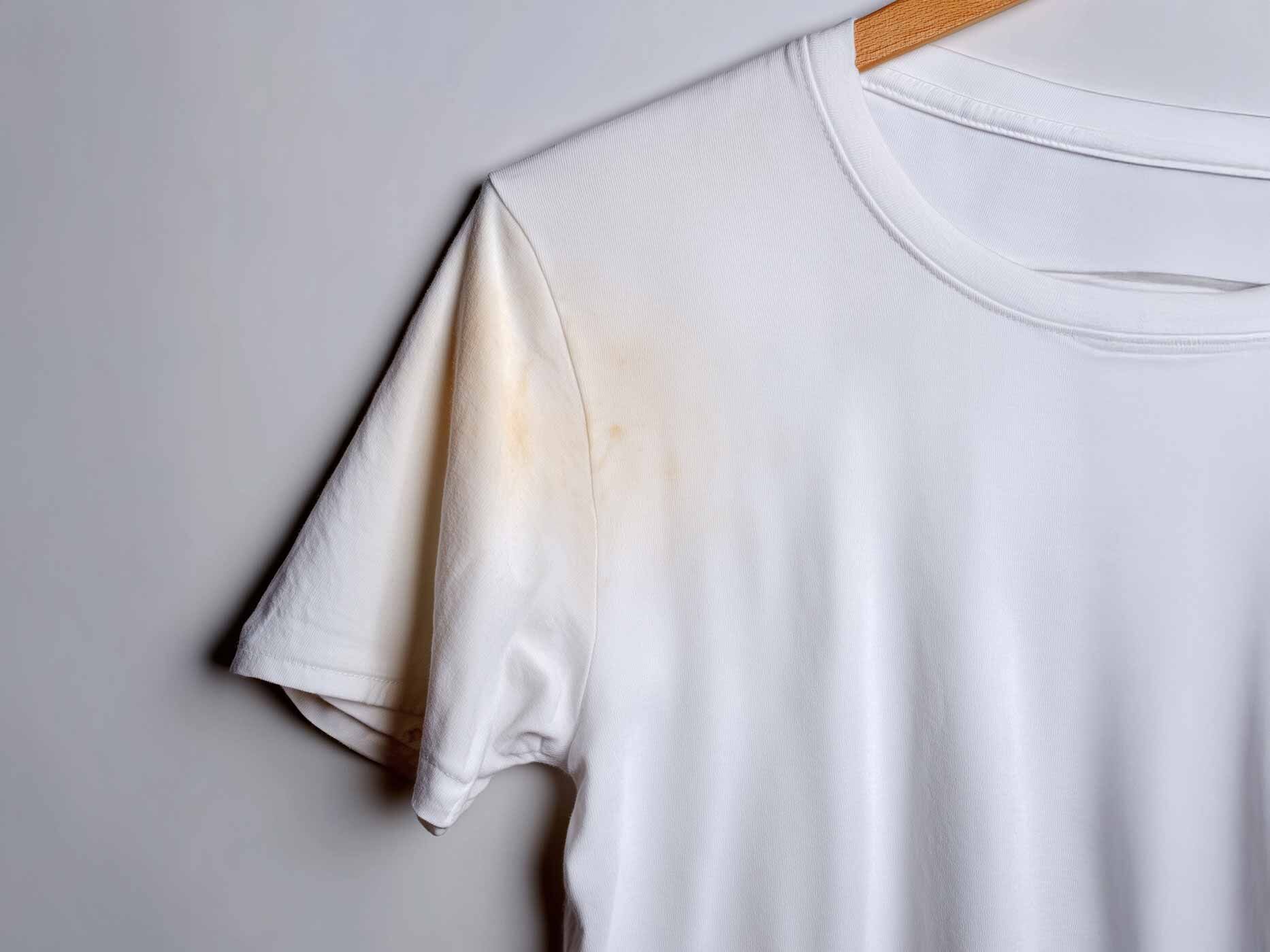 Auf einem weißen T-shirt sind im Achselbreich geöbe Verfärbungen zu sehen.