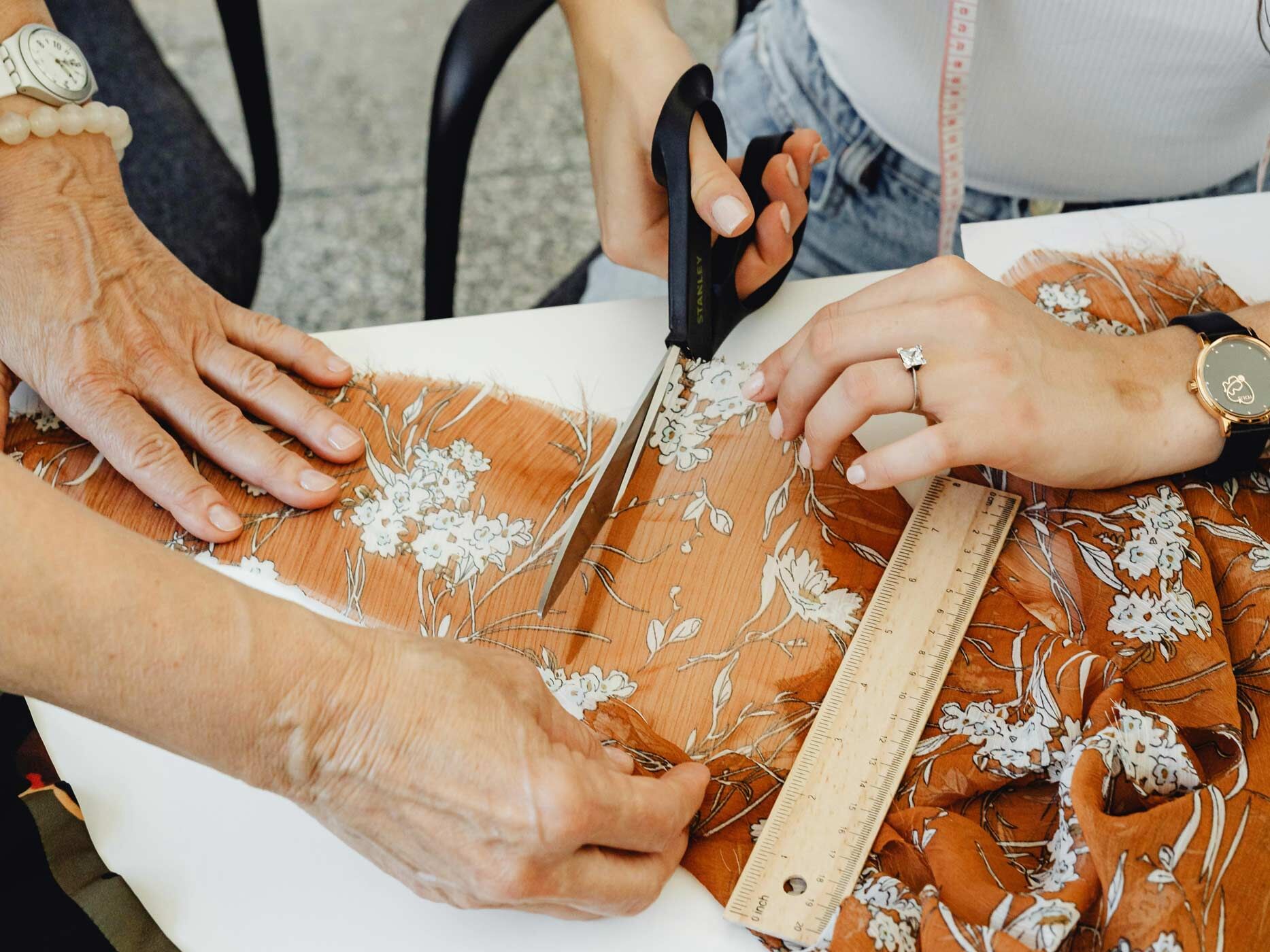 Eine Frau schneidet mit einer Schere an einem bunt gemusterten Kleid entlang.