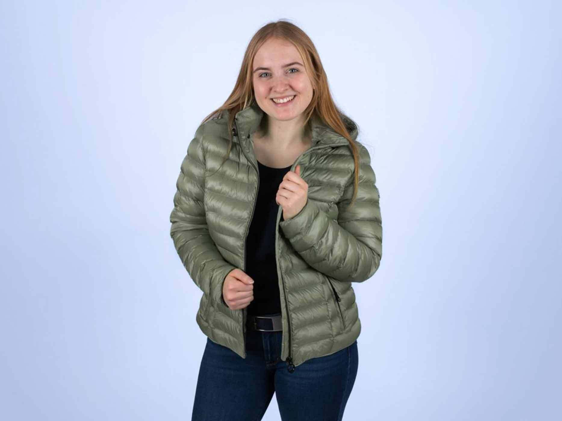 Junge Frau tr&auml;gt die Wellensteyn Italy Hood in Salbeigr&uuml;n offen und l&auml;chelt in die Kamera.