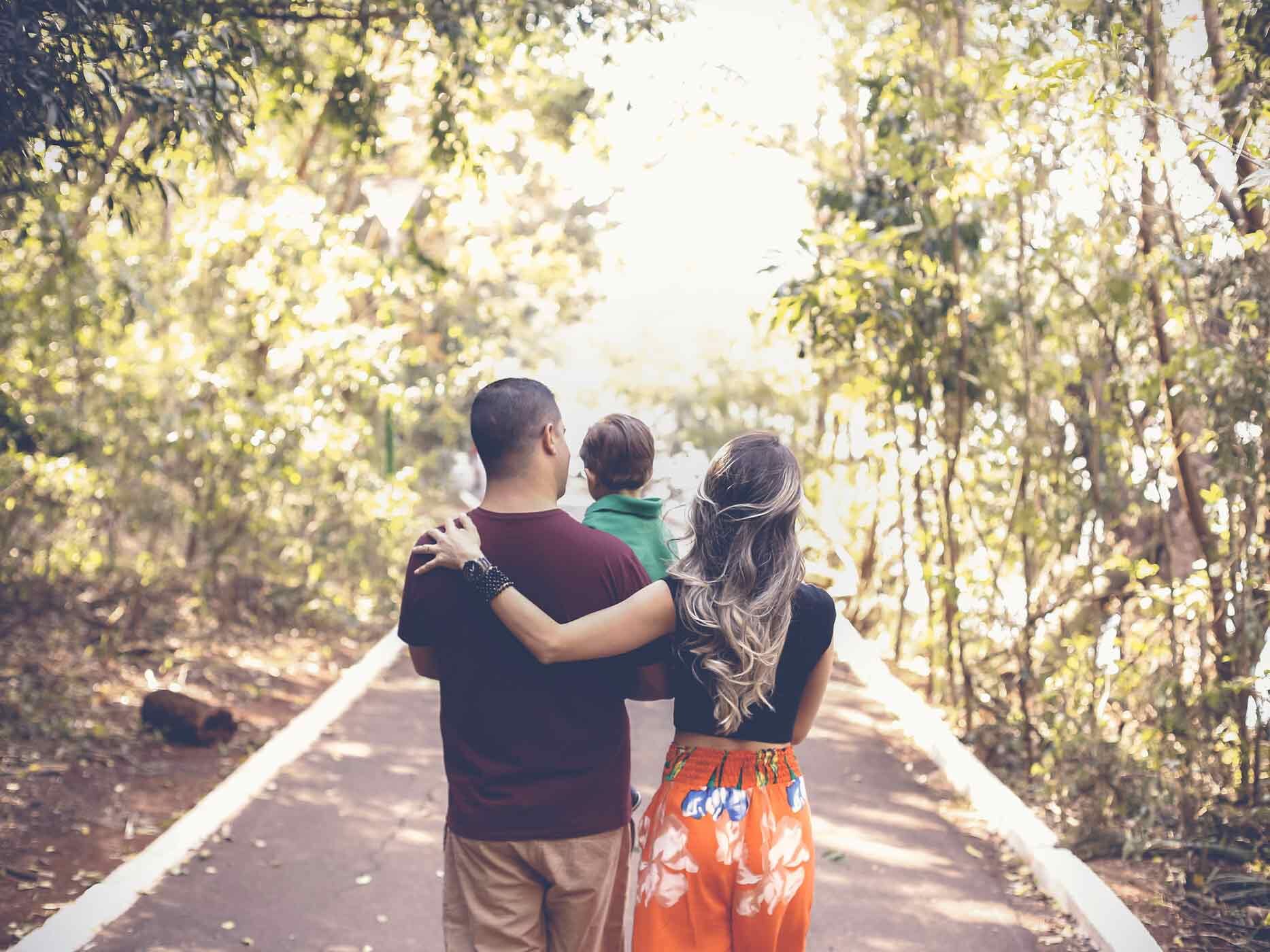 Ein Mann und eine Frau gehen spazieren, sie halten ein Kind auf dem Arm.