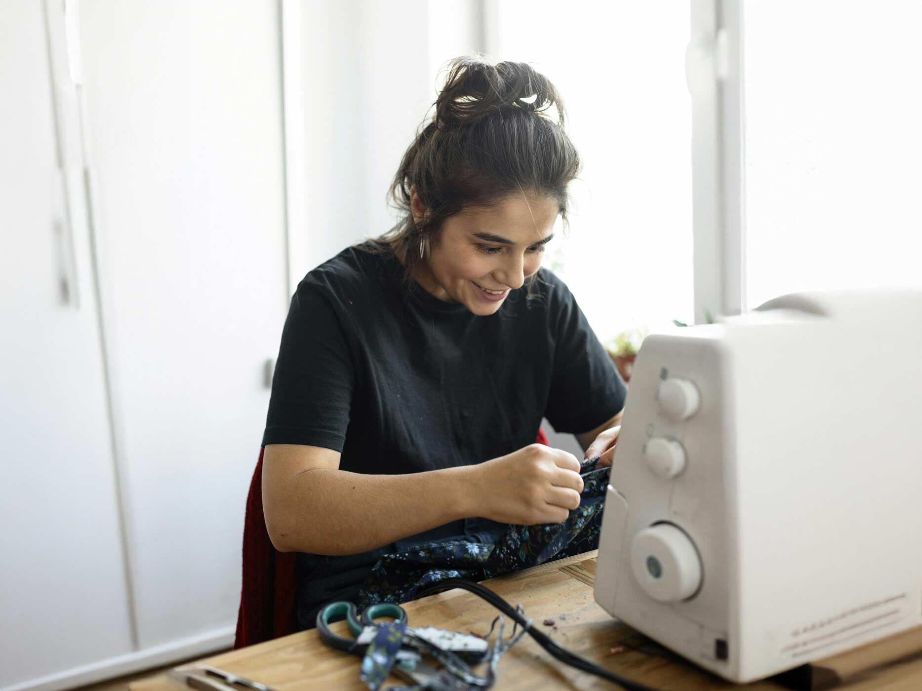 Eine Frau sitzt an einer Nähmaschine und näht.