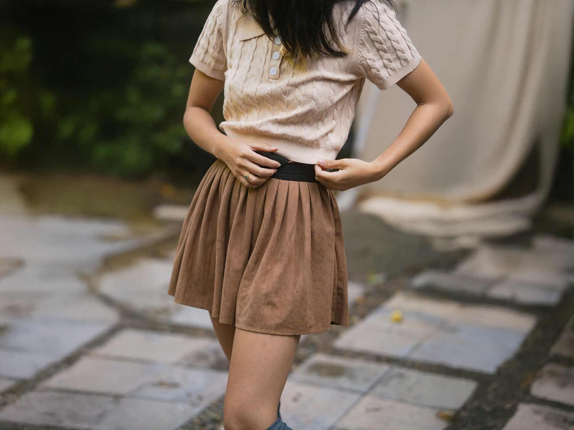 Eine Frau befestigt einen Gürtel am Rockbund.