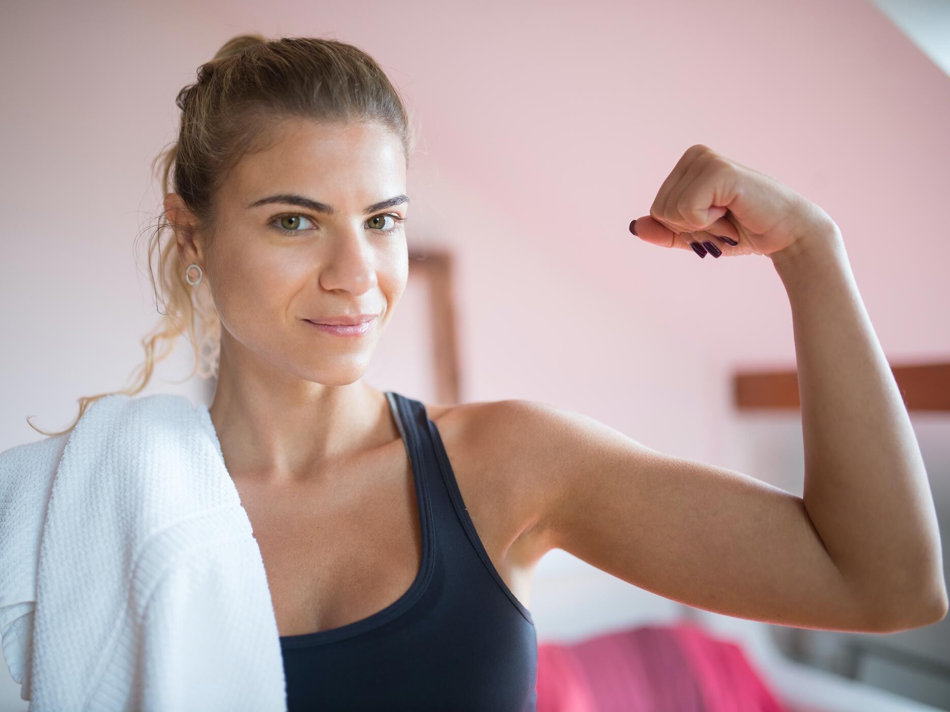 Frau im Sportdress zeigt ihren angespannten Bizeps