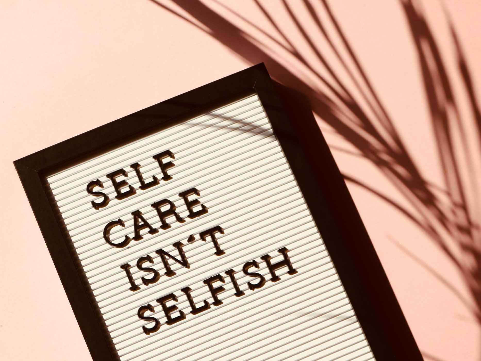 Auf einer Tafel steht mit Buchstaben gelegt der Spruch "Selfcare isn't selfish".