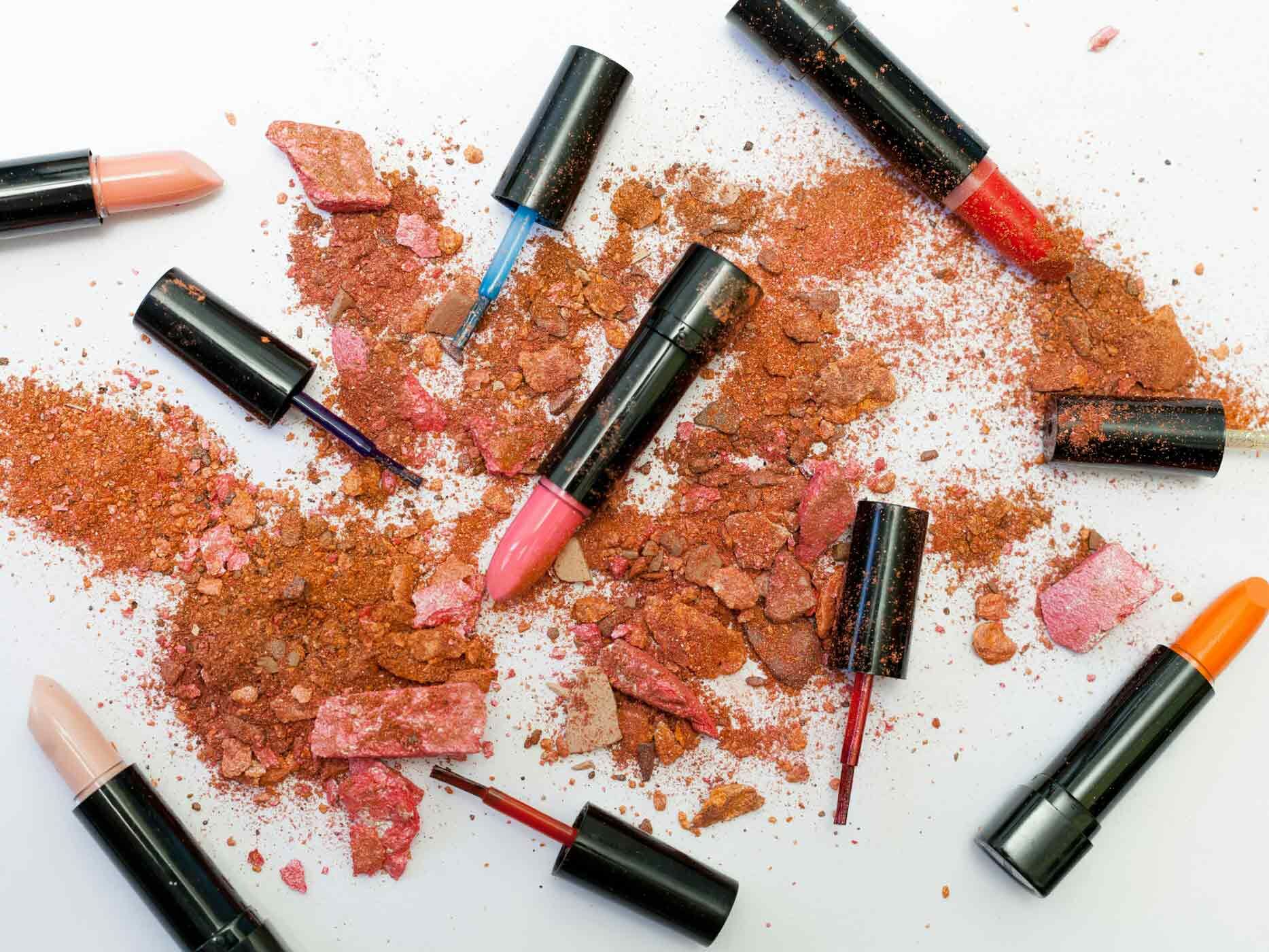 Mehrere ausgefahrene Lippenstifte liegen in zerbröseltem Make-Up Puder