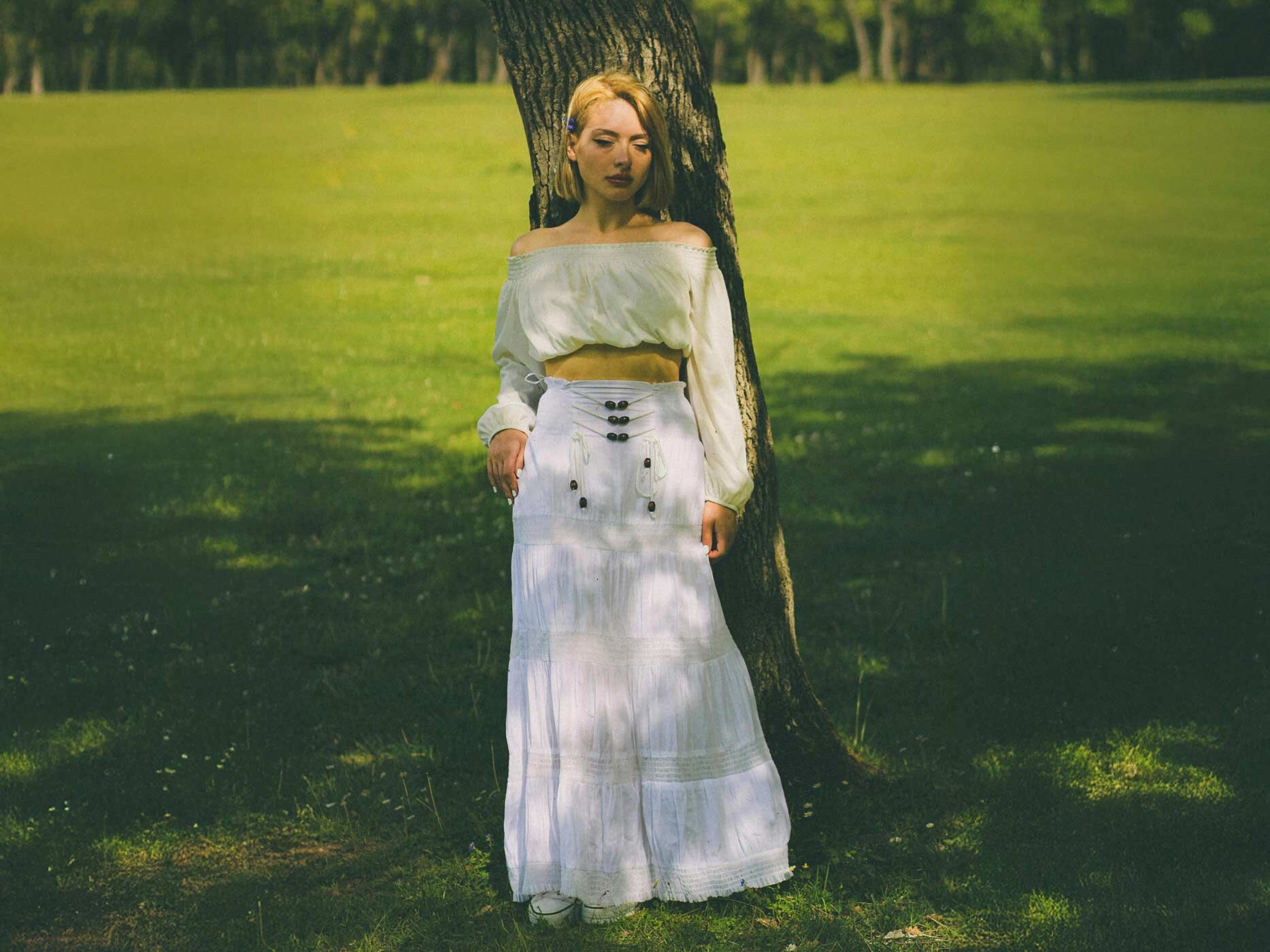 Frau in einem Rock vor einem Baum im Sommer