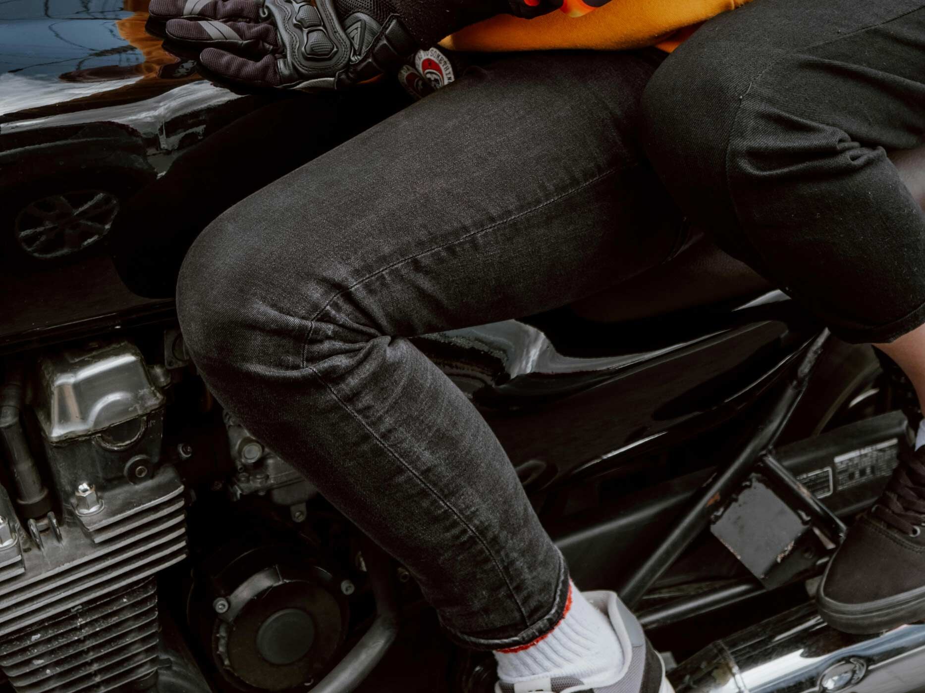 Ein Mensch mit schwarzer Hose sitzt auf einem Motorrad